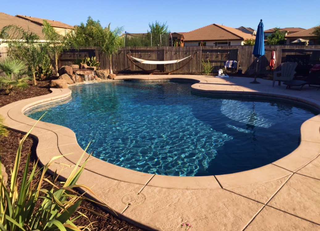 Freeform pool with tan coping and hammock.