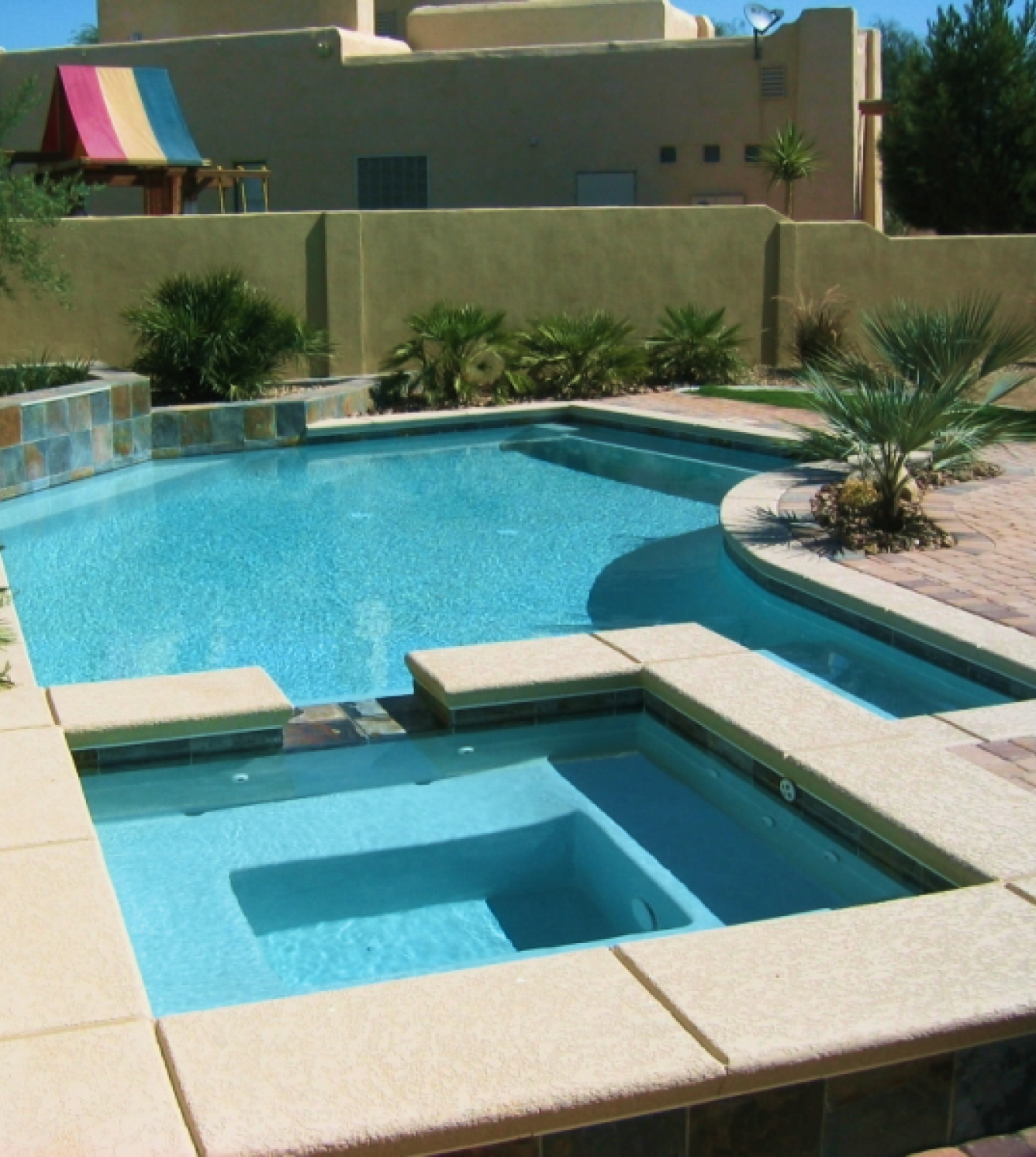 Here's an alt tag for the image: Swimming pool with spa and desert landscaping.